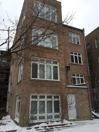 Front view of a multi-story brick building with multiple windows.