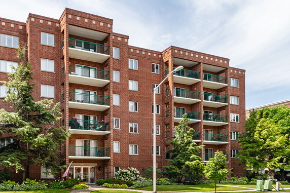 Front view of a multi-story brick apartment building with balconies.