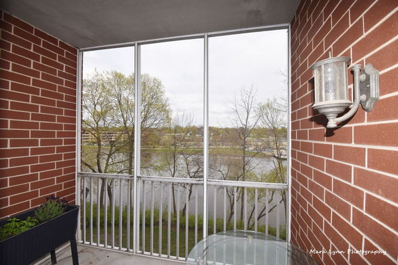 View from a balcony with railing overlooking a river and trees.