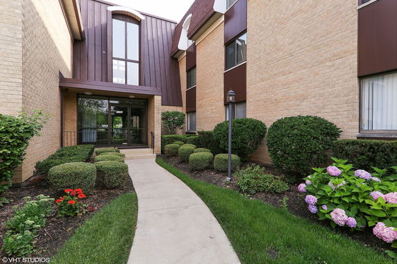 Front view of a brick building entrance with landscaped pathway.