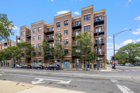 Front view of a four-story brick apartment building with balconies.