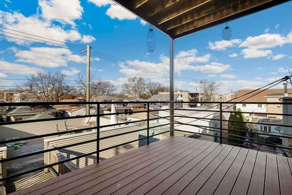 Panoramic view from a balcony overlooking a residential area with rooftops and a clear sky.