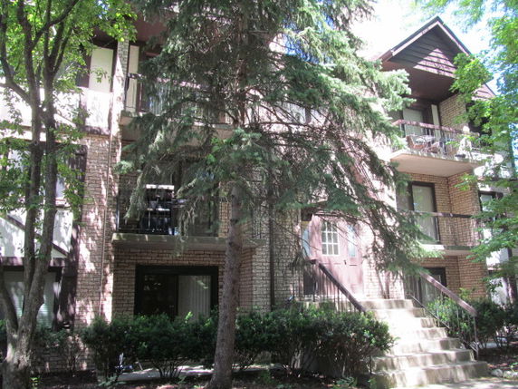 Front view of a multi-story building with balconies and brick facade.