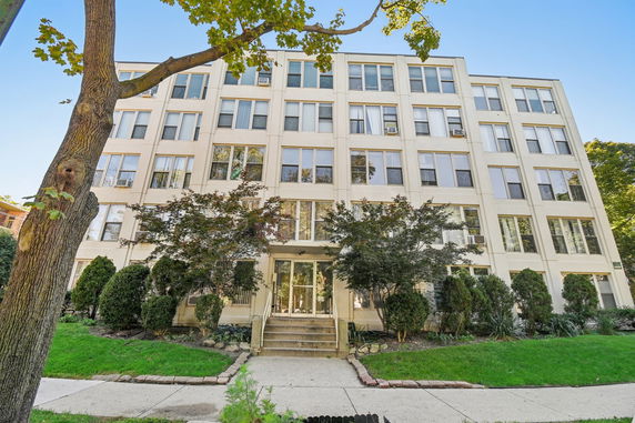 Front view of a multi-story residential building with large windows.