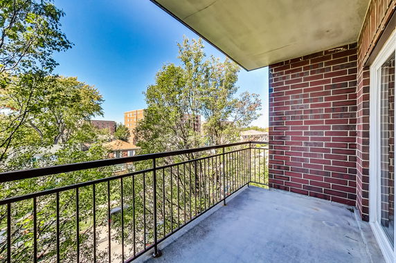Balcony view from a building showing trees and distant buildings.