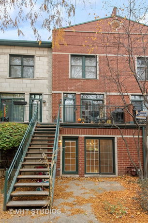 Front view of a multi-story brick house with exterior staircase.