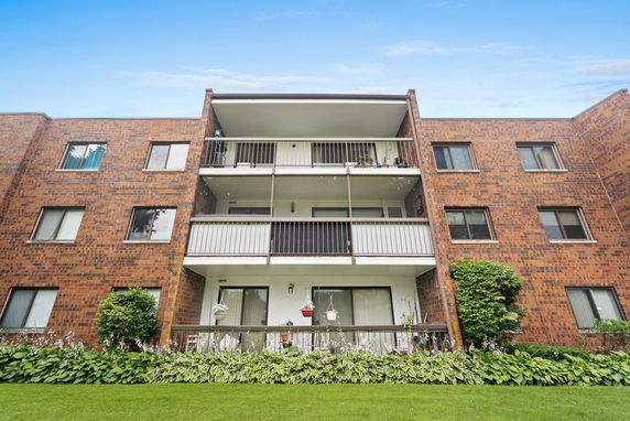 Front view of a multi-story brick apartment building with balconies.