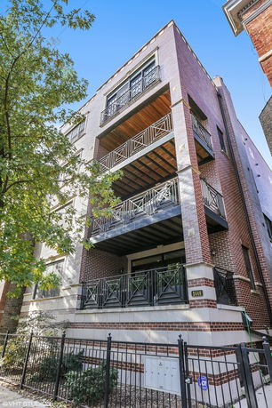 Front view of a multi-story building with balconies and a brick exterior.