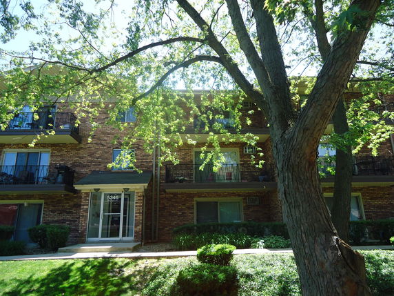 Front view of a multi-story brick apartment building with balconies.