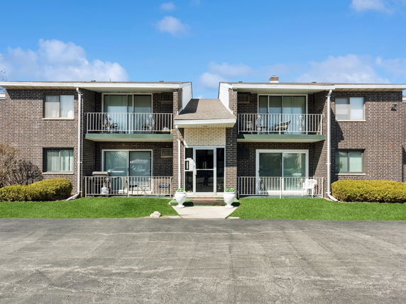 Front view of a two-story apartment building with balconies and brick exterior.
