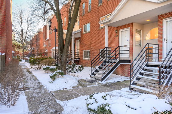 Brick houses with staircases leading to front doors, lined along a snowy walkway.