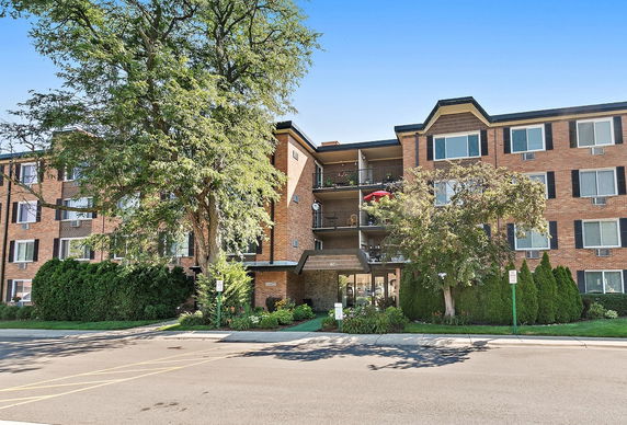 Front view of a multi-story brick apartment building with balconies.