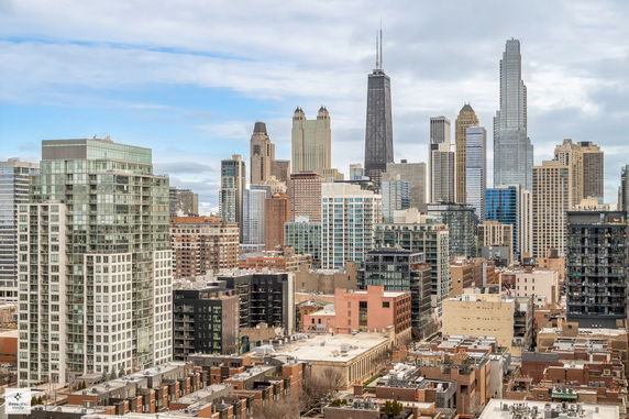 Cityscape view with numerous skyscrapers and buildings under a partly cloudy sky.