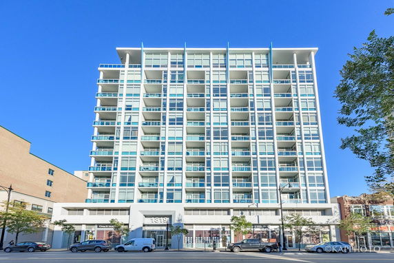 Front view of a tall modern apartment building with multiple balconies.