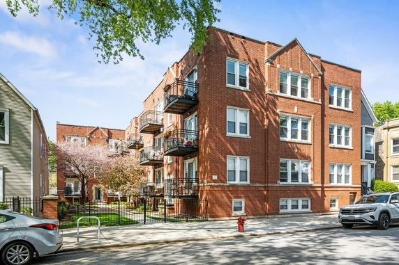 Front view of a multi-story brick apartment building with balconies.