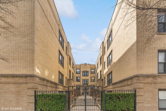 Front view of a multi-story brick apartment building with gated entrance.