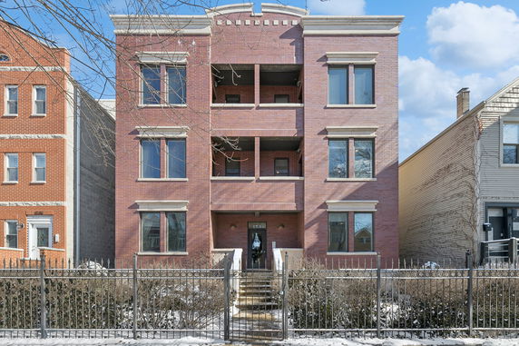 Front view of a three-story brick residential building with multiple windows and a central entrance.