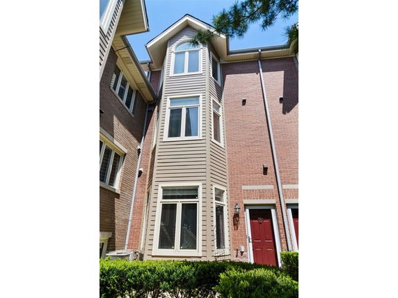 Front view of a three-story townhouse with a brick and siding exterior.
