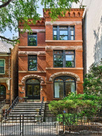 Front view of a three-story brick house with ornate window designs and stone accents.