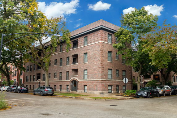 Front view of a multi-story brick building with large windows.