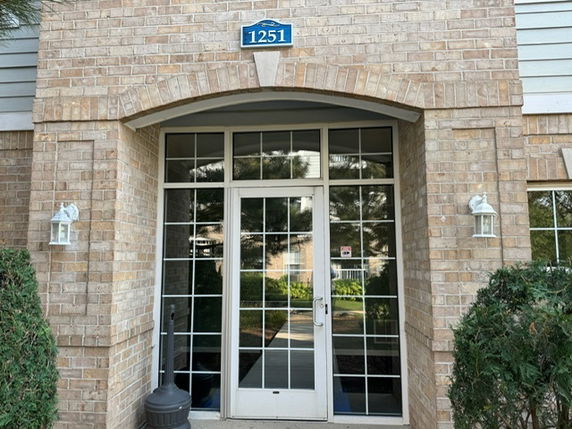 Front view of a brick building entrance with glass doors and windows.