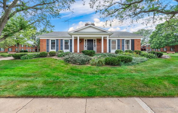 Front view of a single-story brick house with a porch and white columns.