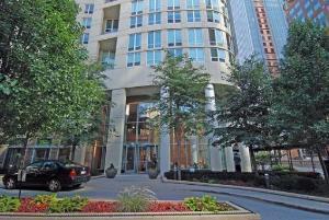 Front view of a modern multi-story building with large windows and trees in the foreground.