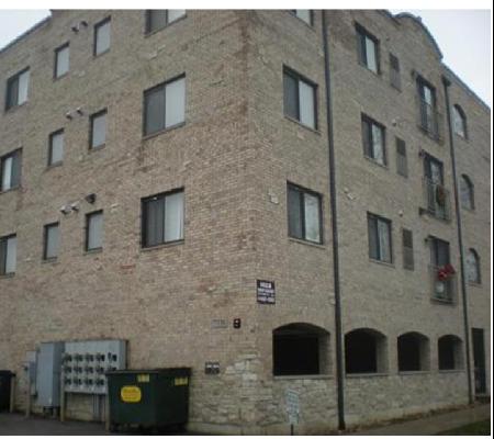 Front and side view of a four-story brick apartment building.