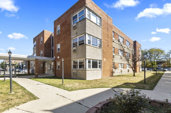 Front view of a multi-story brick apartment building with multiple windows.