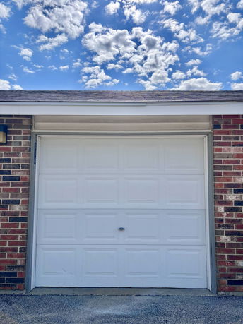 Front view of a garage with a white door in a brick building.
