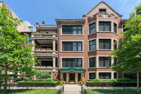 Front view of a multi-story brick building with large windows and a green awning over the entrance.