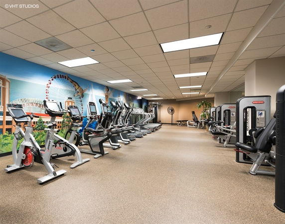Indoor gym area with exercise equipment and a mural on the wall.