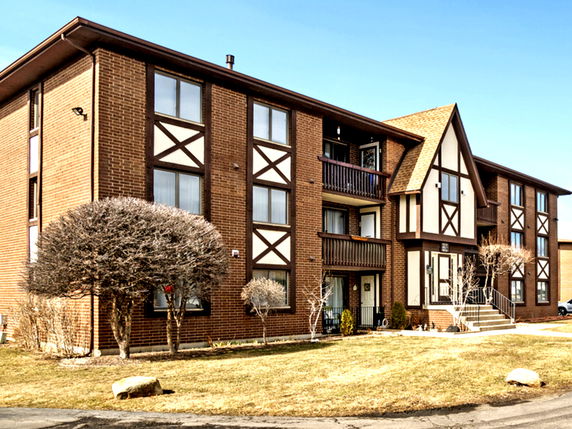 Front view of a multi-story brick building with Tudor-style accents.