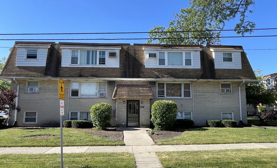 Front view of a two-story residential building with multiple windows and a central entrance.