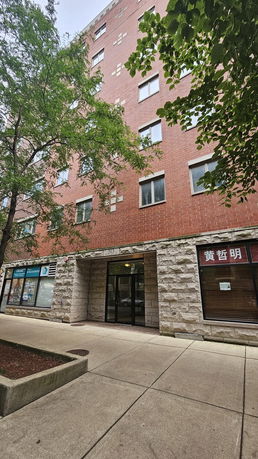 Front view of a multi-story brick building with commercial spaces at the ground level.