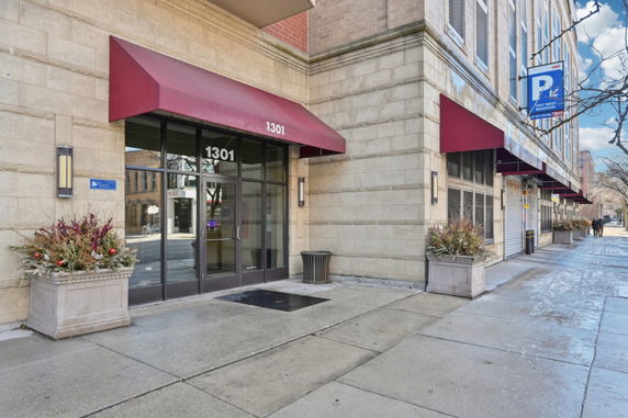 Front view of a building entrance with red awnings and glass doors.