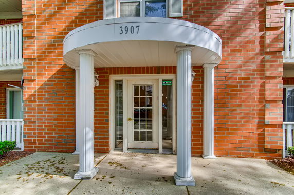 Front view of a brick building entrance with white columns.