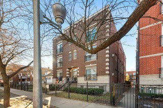 Front view of a multi-story brick building with a gated entrance.
