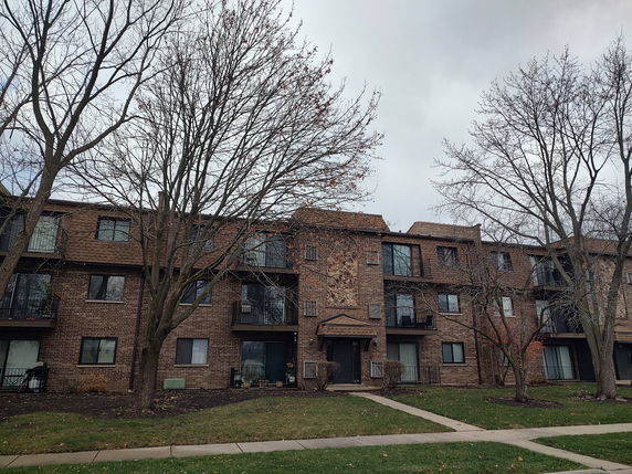Front view of a three-story apartment building with brick facade and balconies.