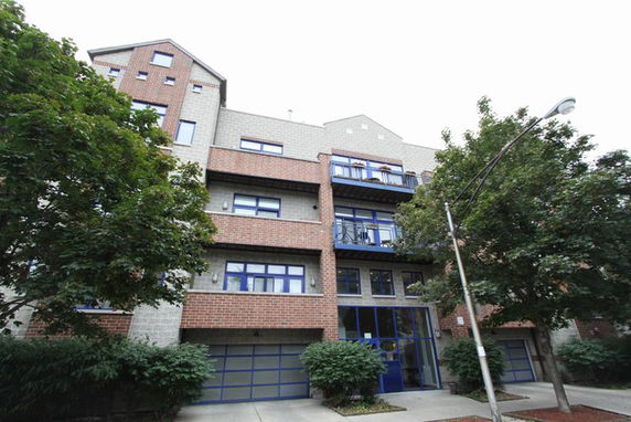 Front view of a multi-story building with a brick facade and blue-framed windows.