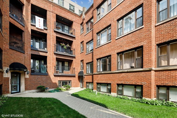 Front view of a multi-story brick apartment building with balconies.