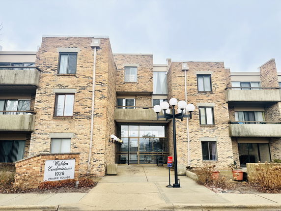 Front view of a multi-story condominium building with brick exterior and balconies.