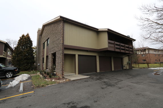 Front view of a two-story house with three garage doors and a balcony.