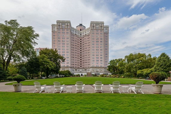 Front view of a tall, multi-story building with numerous windows and a lawn area in the foreground.