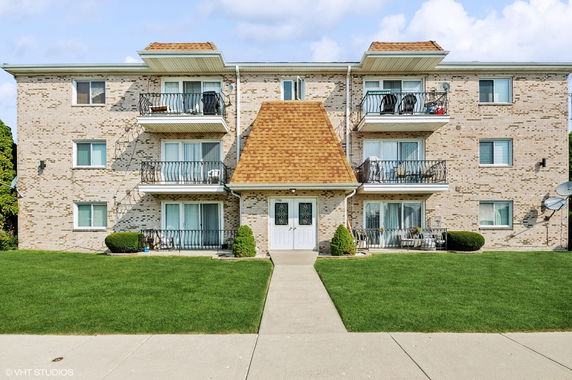 Front view of a three-story apartment building with balconies.