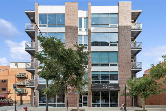 Front view of a multi-story brick building with large windows and balconies.