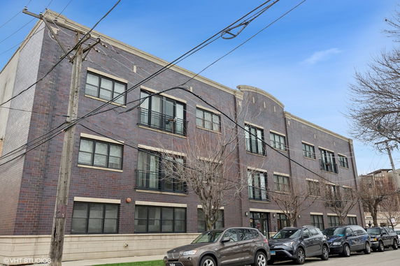 Front view of a multi-story brick building with multiple windows and a flat roof.