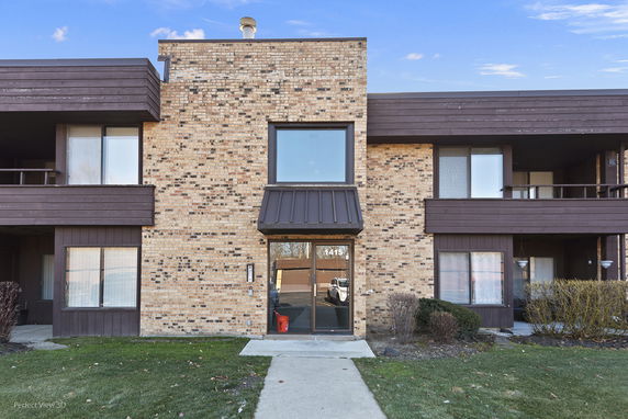 Front view of a brick apartment building with glass entry doors.