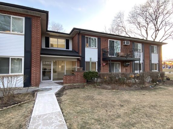 Front view of a two-story brick apartment building with balconies and multiple windows.