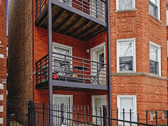 Front view of a brick apartment building with balconies.